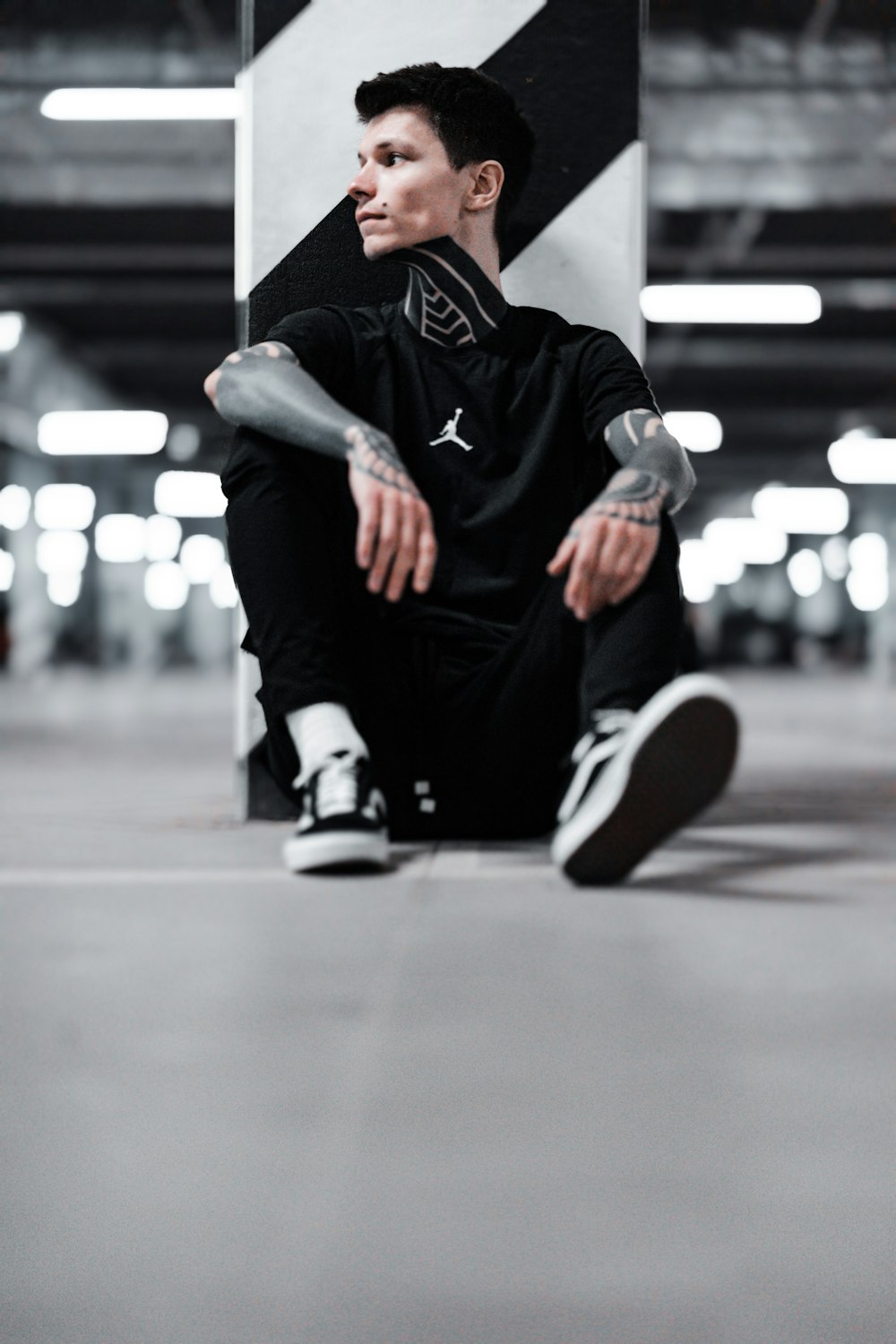 man in black and white nike sneakers sitting on floor