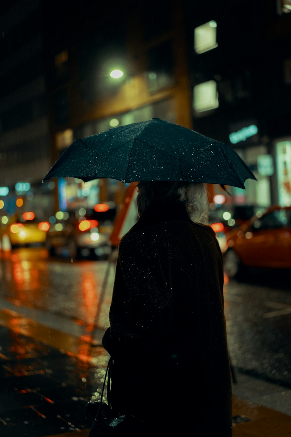 person in black coat holding umbrella