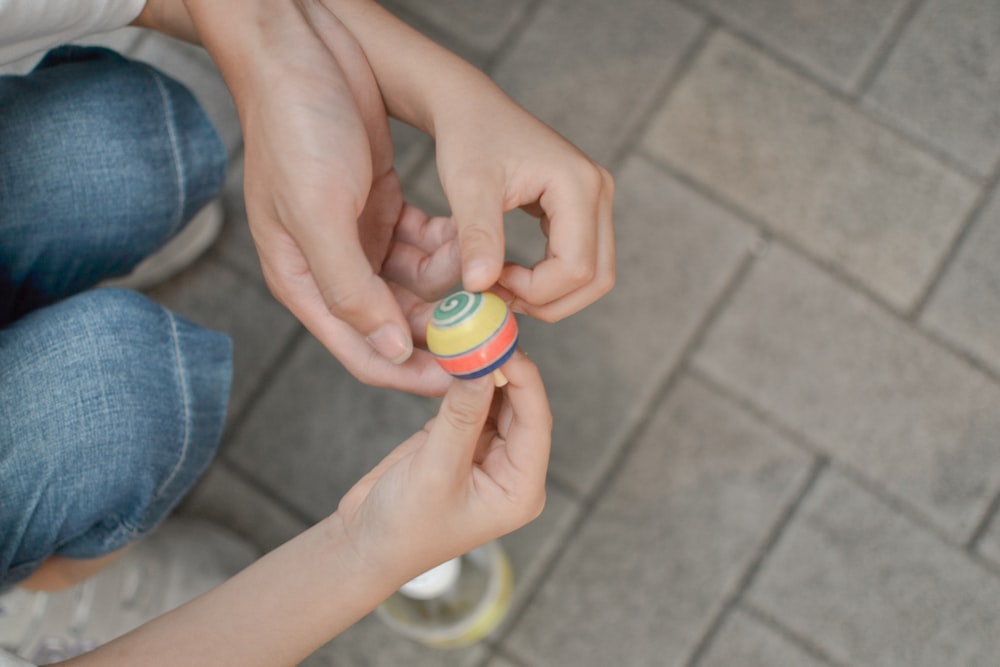 person holding green yellow and blue round plastic