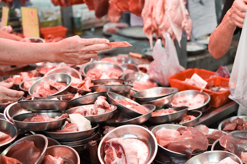 person holding a stainless steel bowl with raw meat