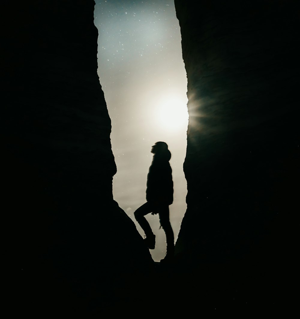 silhouette of man standing on rock formation during daytime