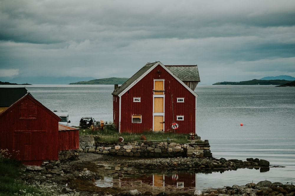 red and white wooden house near body of water during daytime