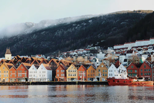 houses near body of water and mountain during daytime