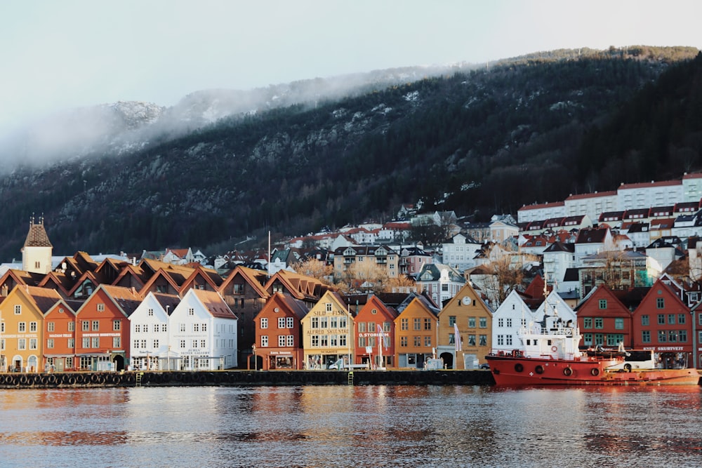 houses near body of water and mountain during daytime