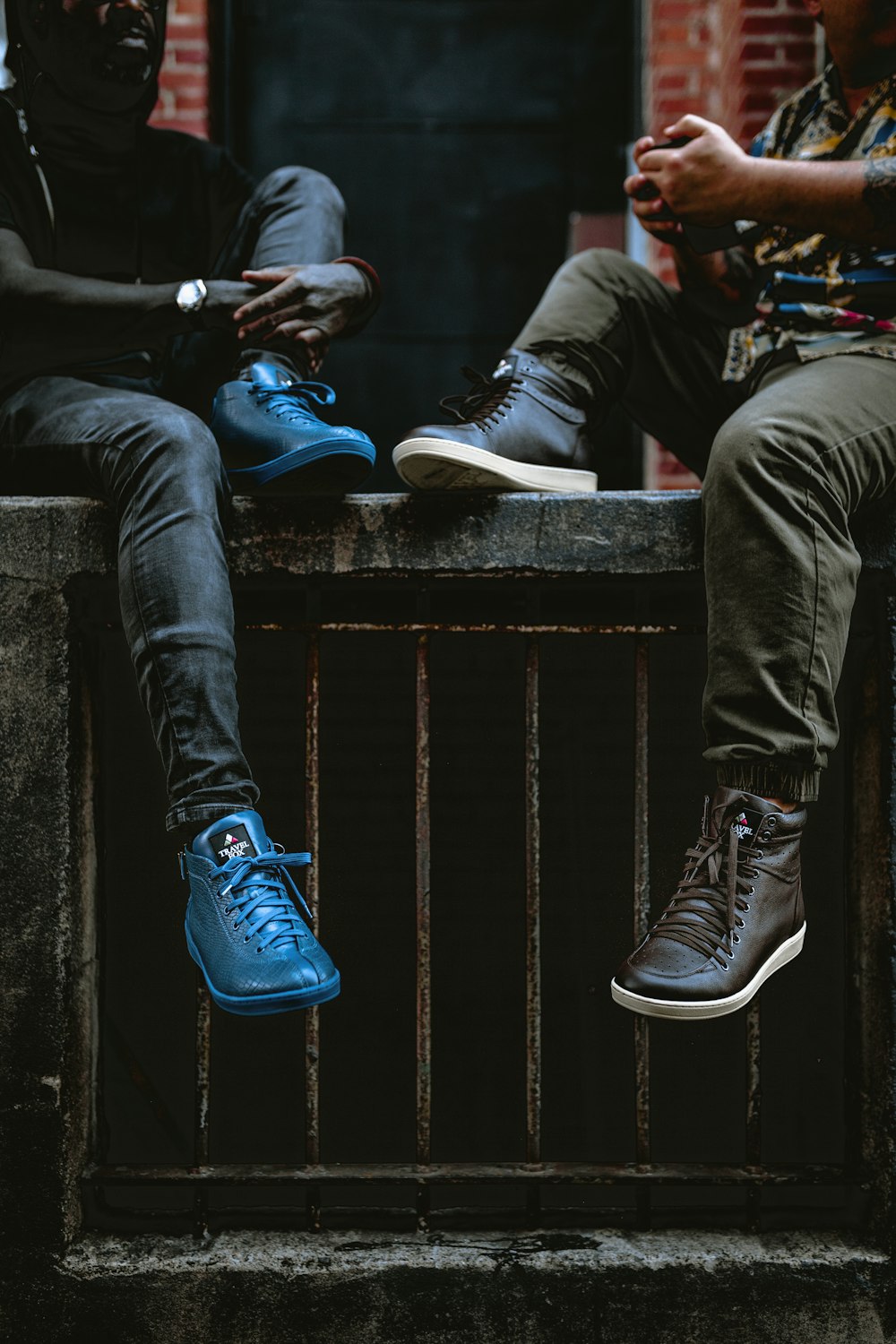 man in black pants and blue nike shoes sitting on black concrete stairs