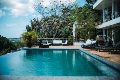 woman in black shirt sitting on white chair near swimming pool during daytime