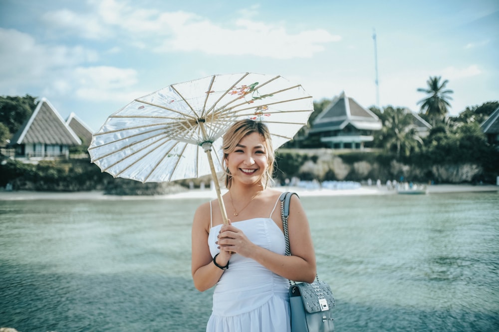 woman in white spaghetti strap dress holding white umbrella