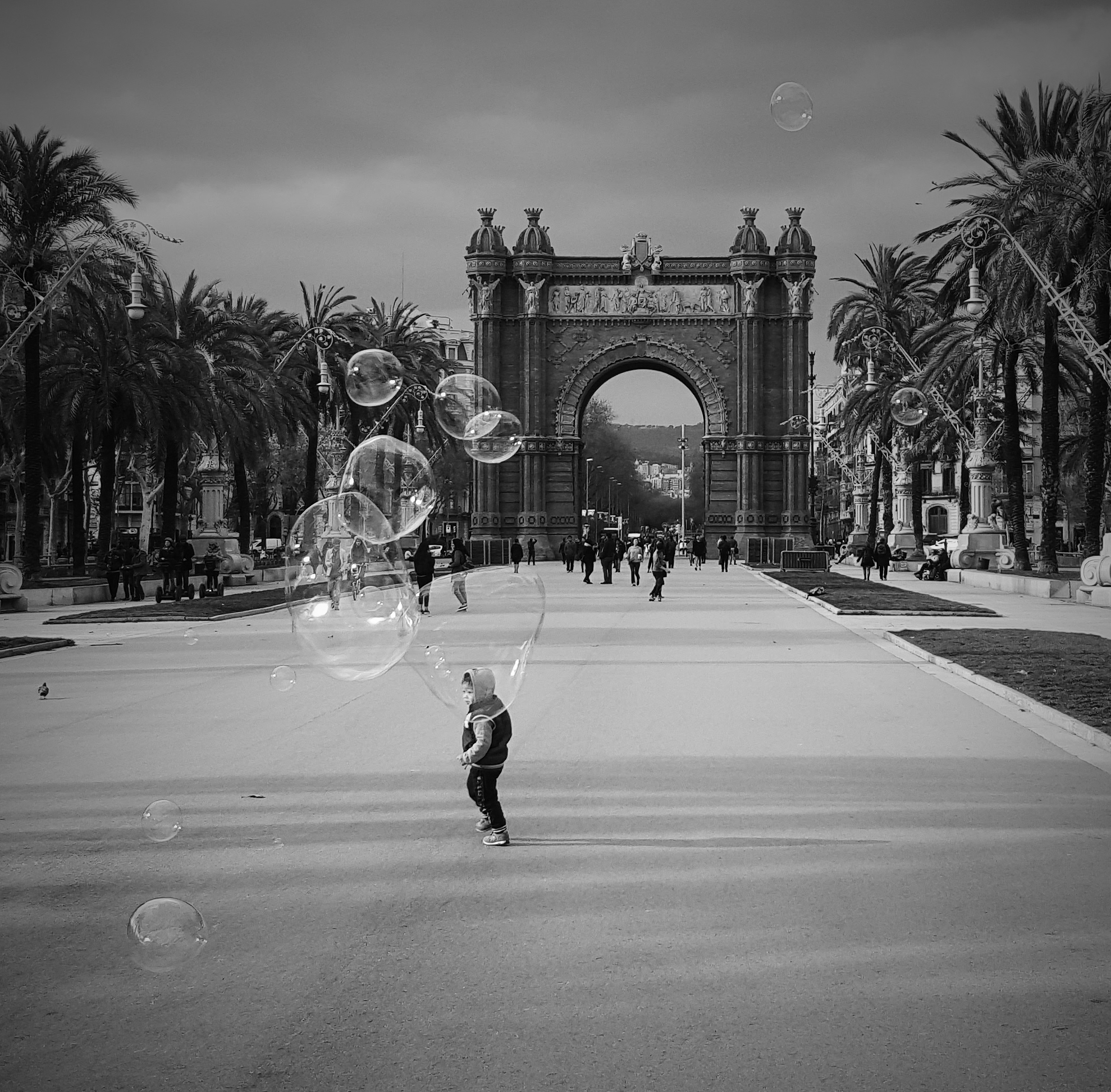 grayscale photo of girl playing bubbles on road