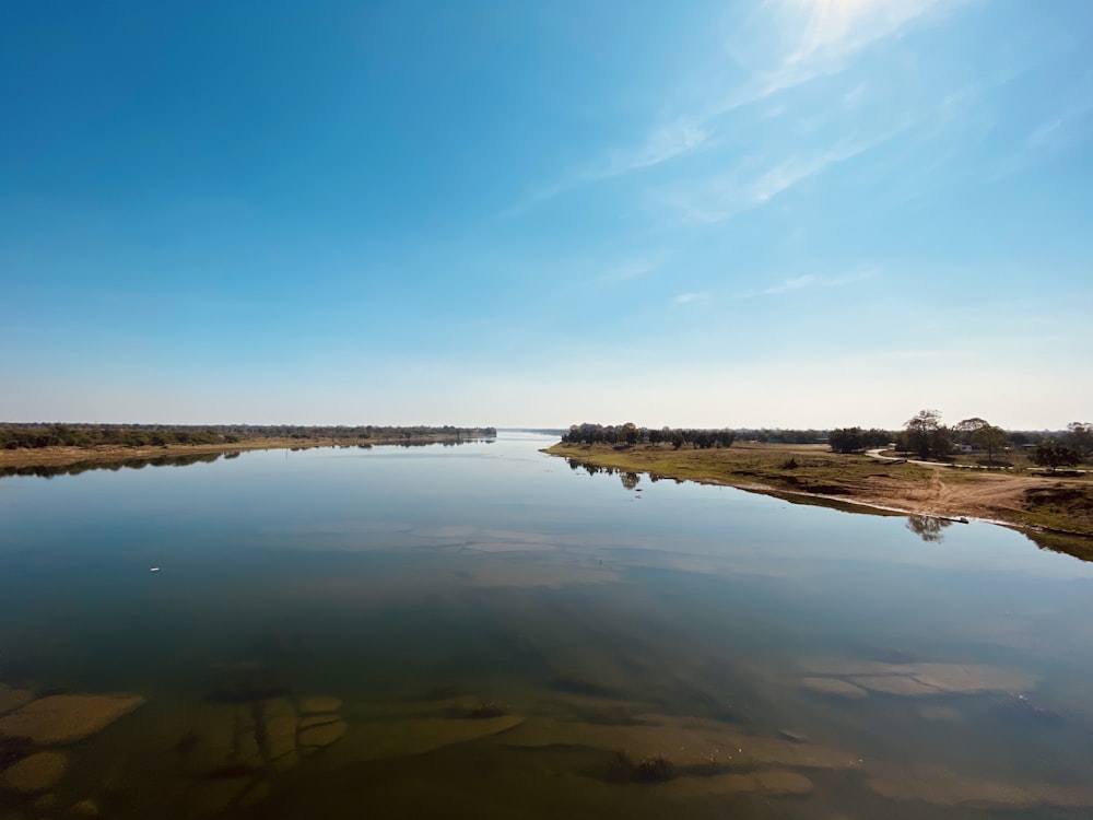 body of water near brown land under blue sky during daytime