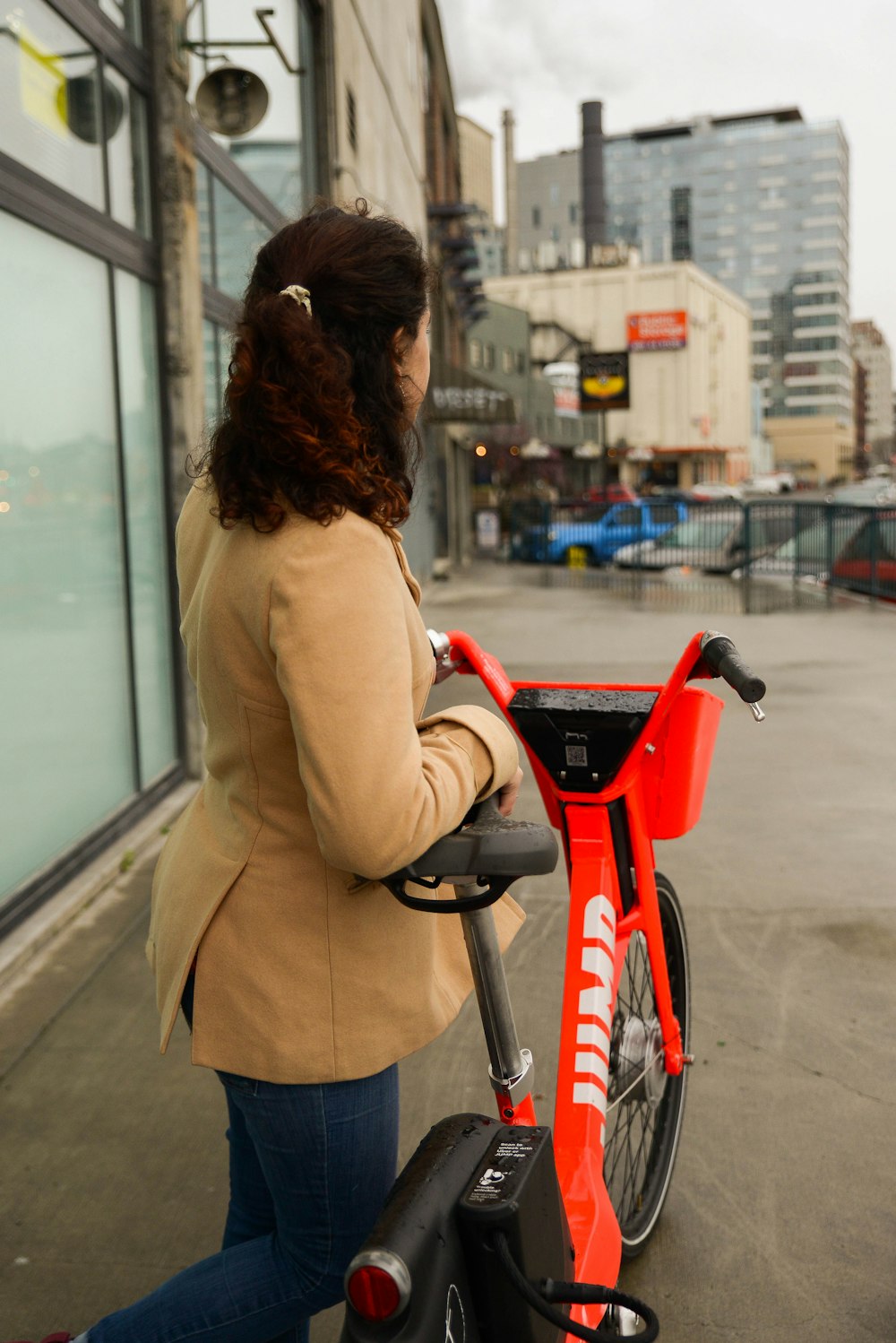 woman in beige coat riding red bicycle during daytime