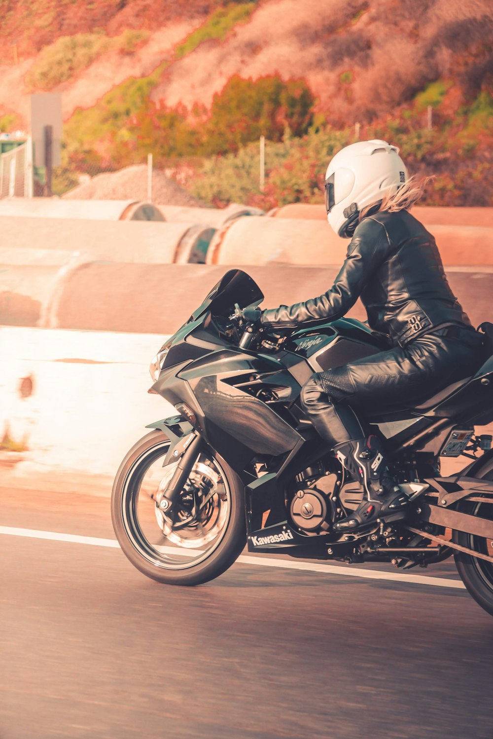 homme en veste en cuir noir conduisant une moto de sport noire sur la route pendant la journée