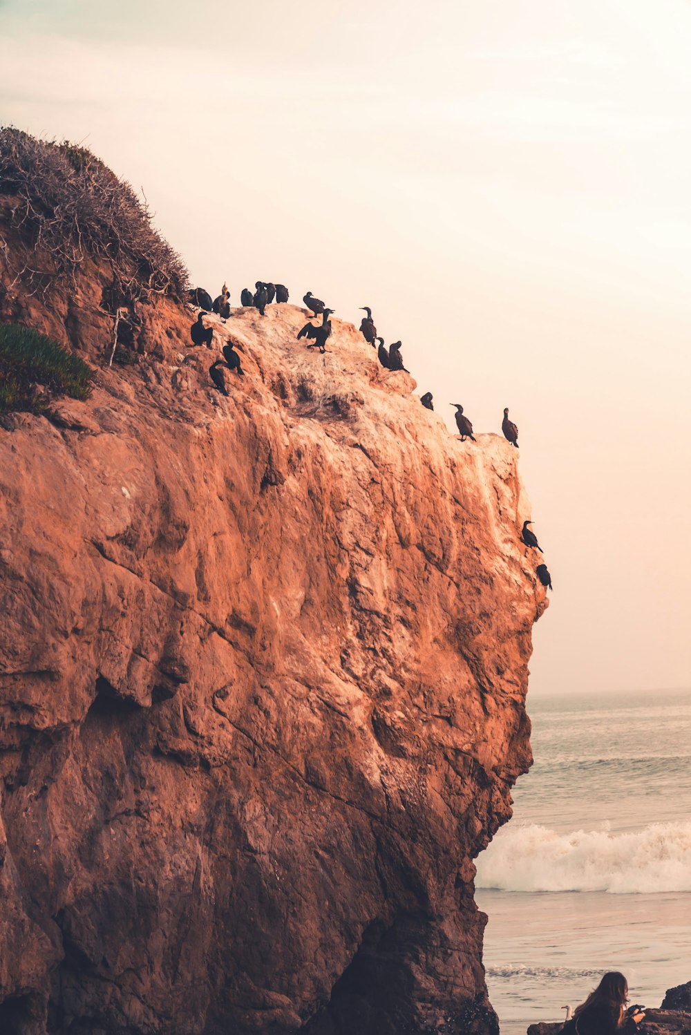 people standing on brown rock formation near sea during daytime