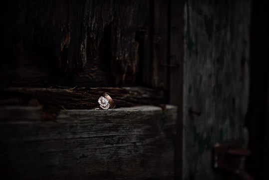 Close-up of a vintage-style ring set with a vibrant emerald on a wooden surface.