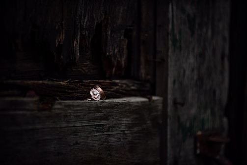 Close-up of a rugged silver ring etched with ancient runes, resting on a weathered wooden surface.