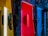 A room illuminated with vibrant colored lights including yellow, red, and blue. Curtains with graffiti-style patterns separate the sections, and there are round mirrors mounted on the walls reflecting the colorful decor. The space seems artistic and modern, enhanced by reflective surfaces.
