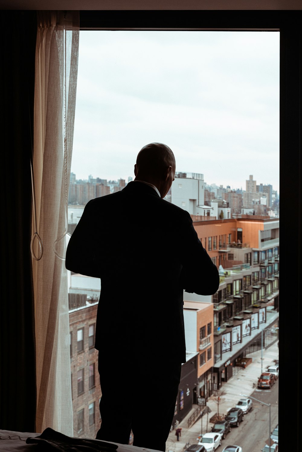 uomo in camicia nera in piedi vicino alla finestra durante il giorno