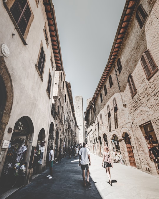 people walking on street between buildings during daytime in San Gimignano Italy