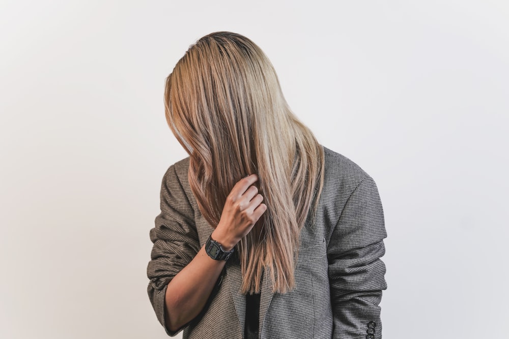 donna in camicia grigia a maniche lunghe che si copre il viso con i capelli