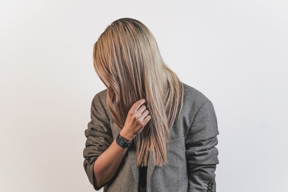 mujer con camisa gris de manga larga cubriendo su rostro con su cabello