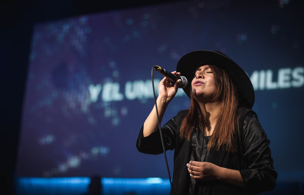 woman in black hat singing