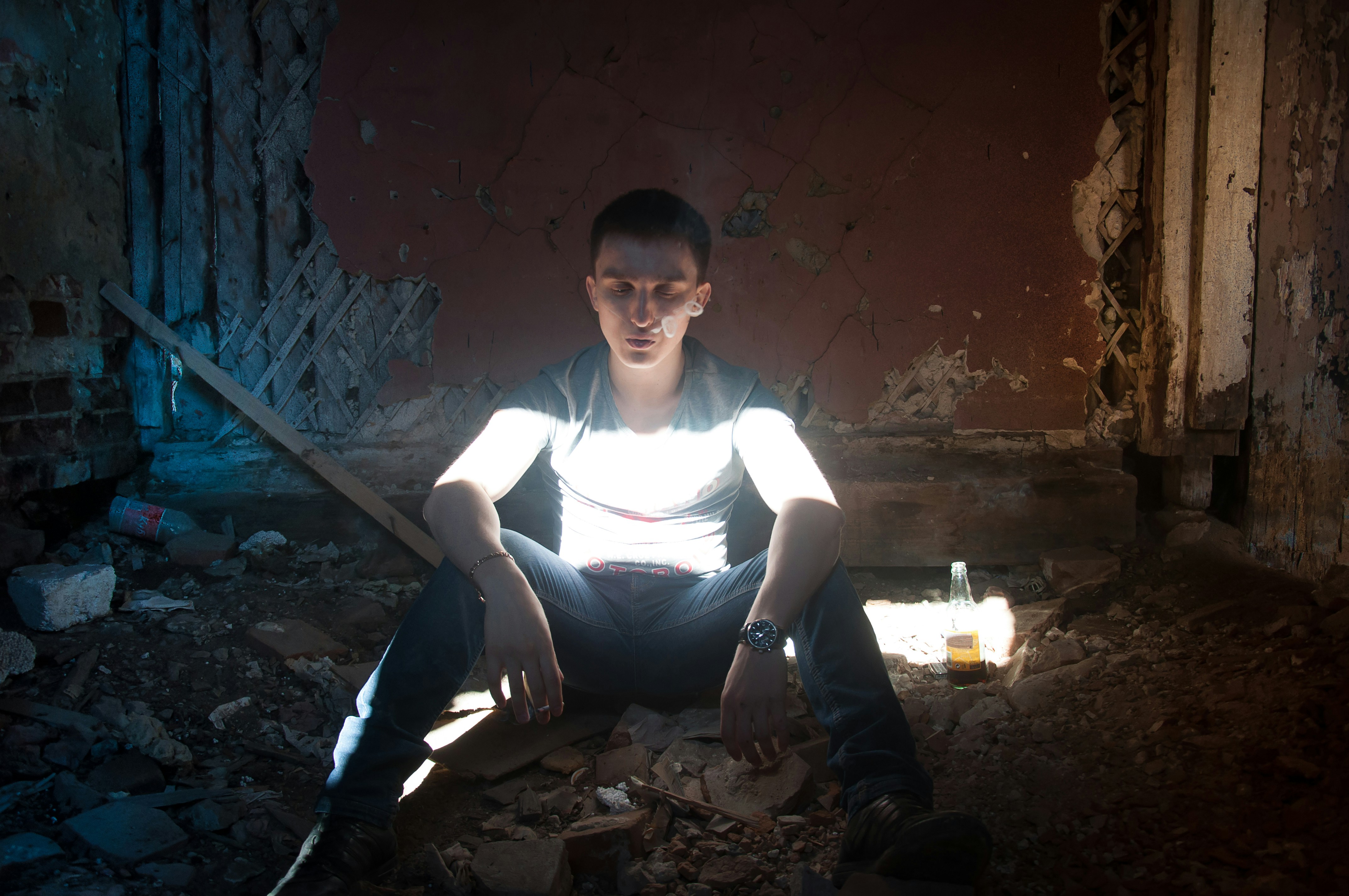 man in white tank top sitting on brown wooden chair
