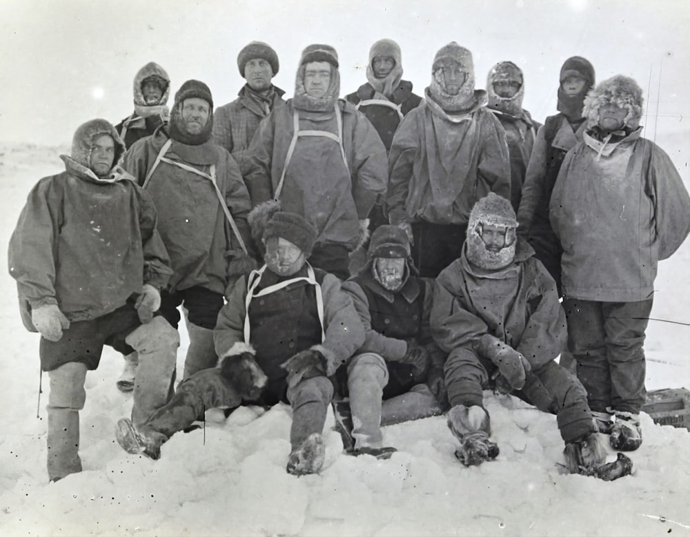 雪に覆われた地面に黒いコートを着た男性のグループ