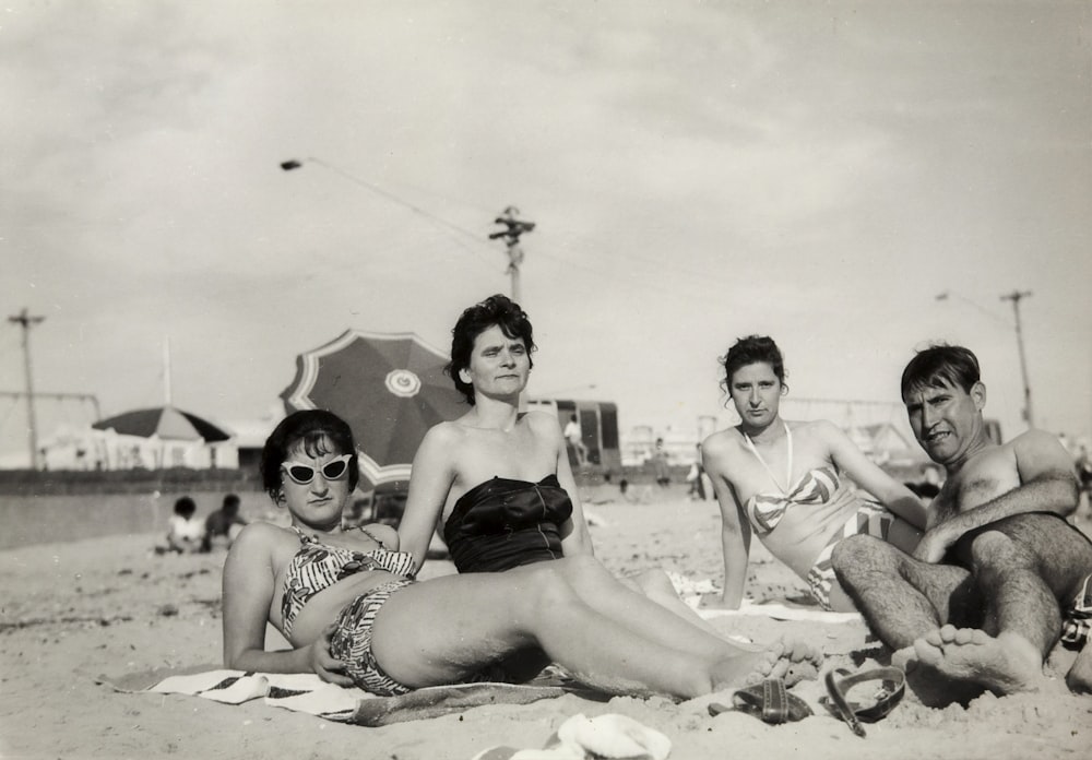 grayscale photo of 3 women sitting on the ground