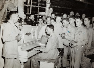 grayscale photo of 4 men standing beside piano