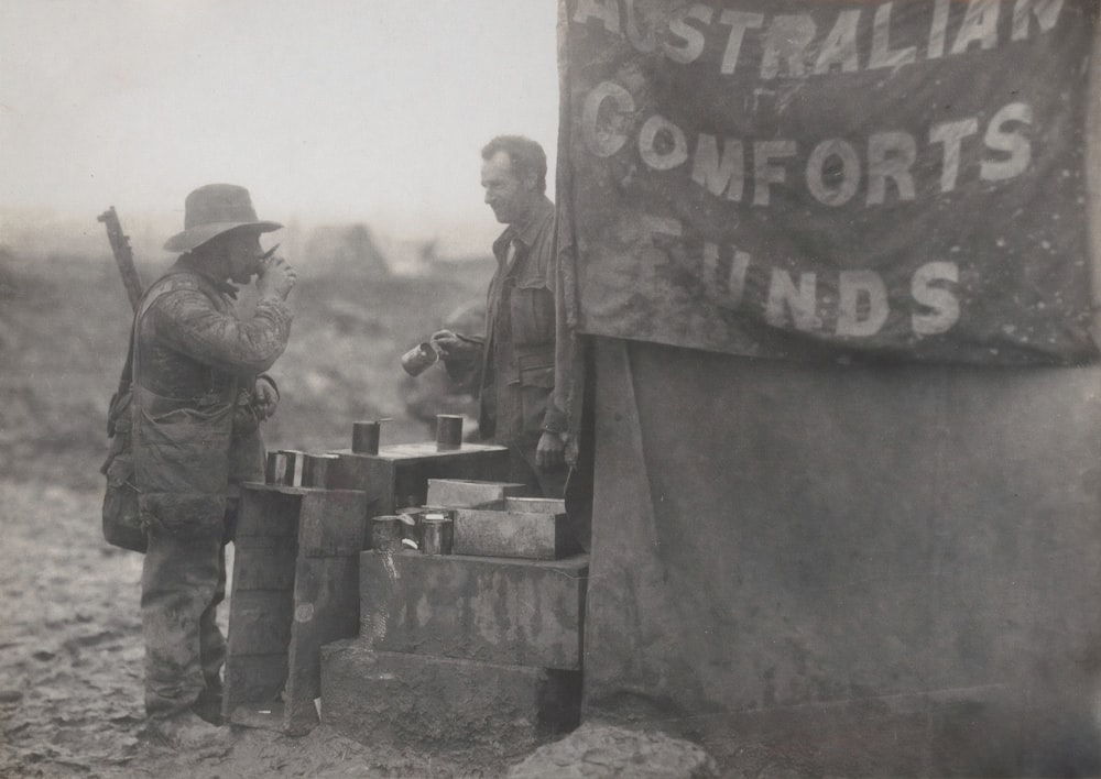 grayscale photo of 2 men standing near wall