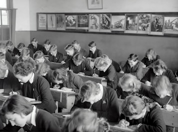 grayscale photo of people sitting on chair