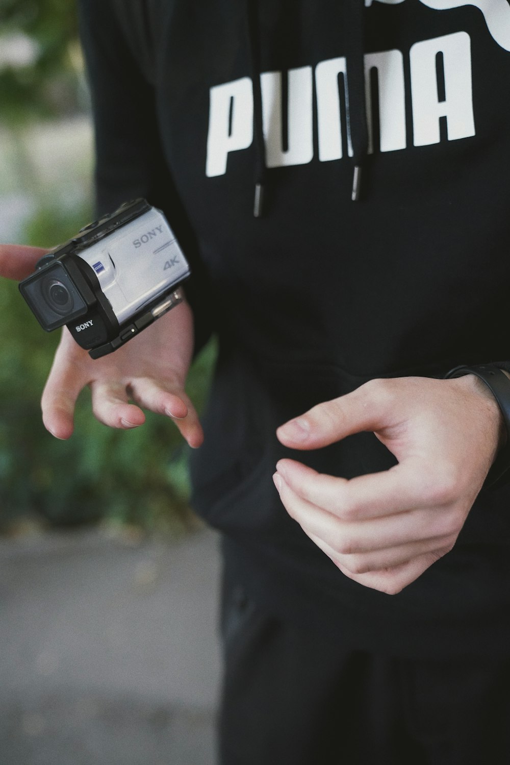 Persona in bianco e nero Nike maglietta a maniche lunghe che tiene il dispositivo elettronico in bianco e nero