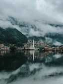 white and red building near body of water under cloudy sky during daytime