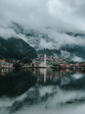 white and red building near body of water under cloudy sky during daytime