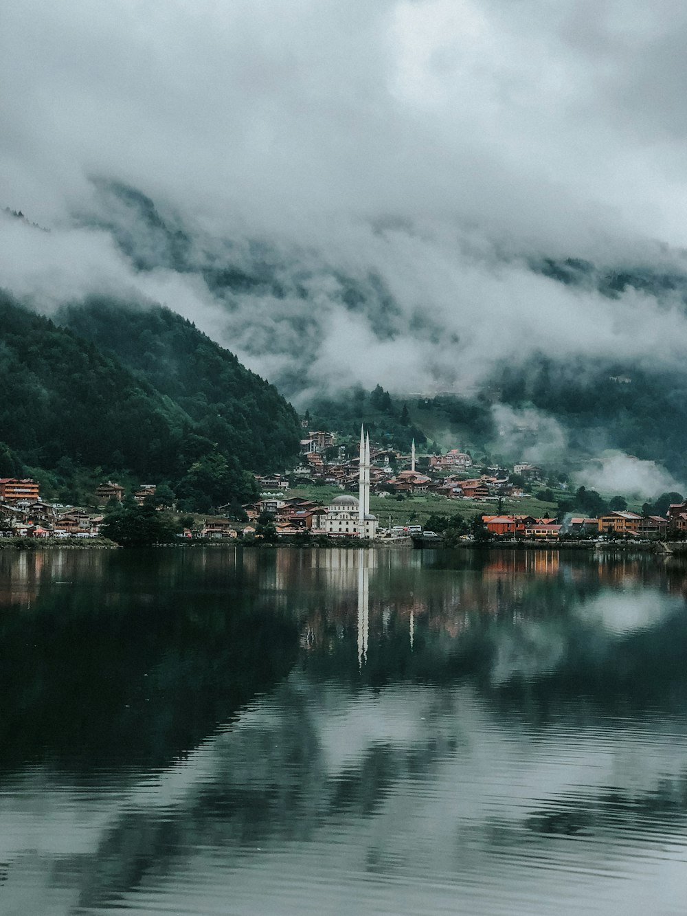 white and red building near body of water under cloudy sky during daytime