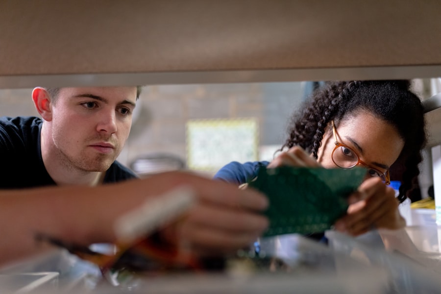 Two students collaborating closely on a circuit board