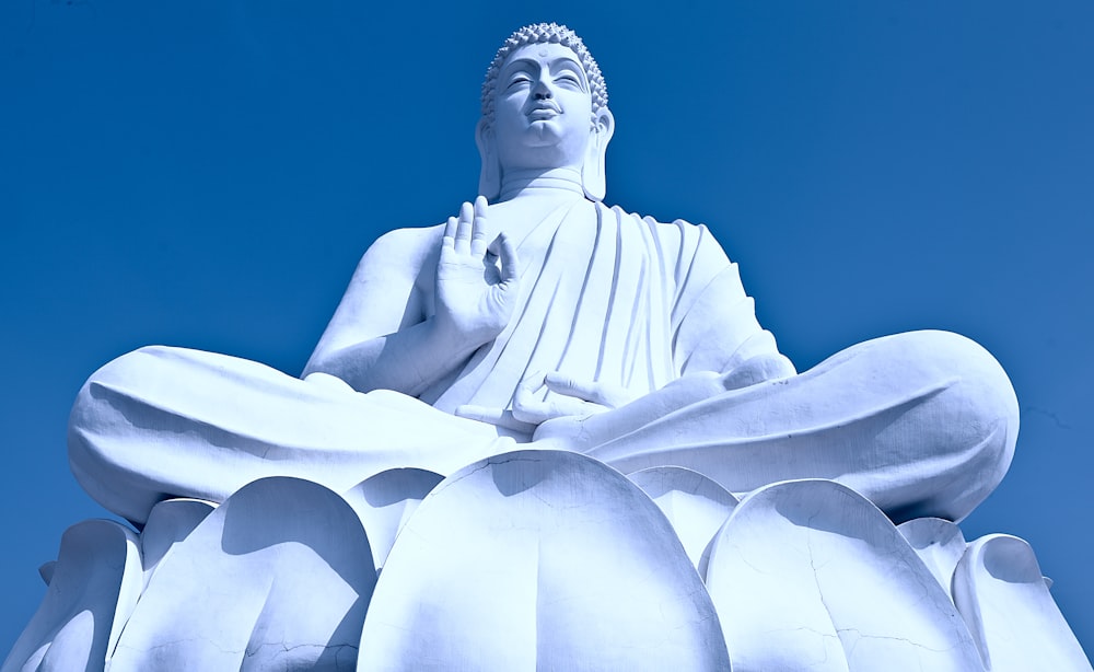 statua di cemento bianco sotto il cielo blu durante il giorno