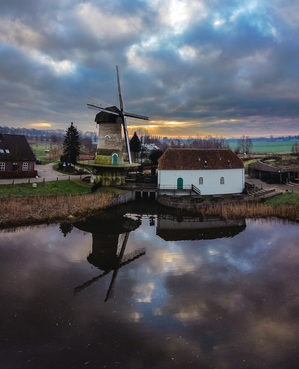 white and brown house beside body of water under cloudy sky during daytime