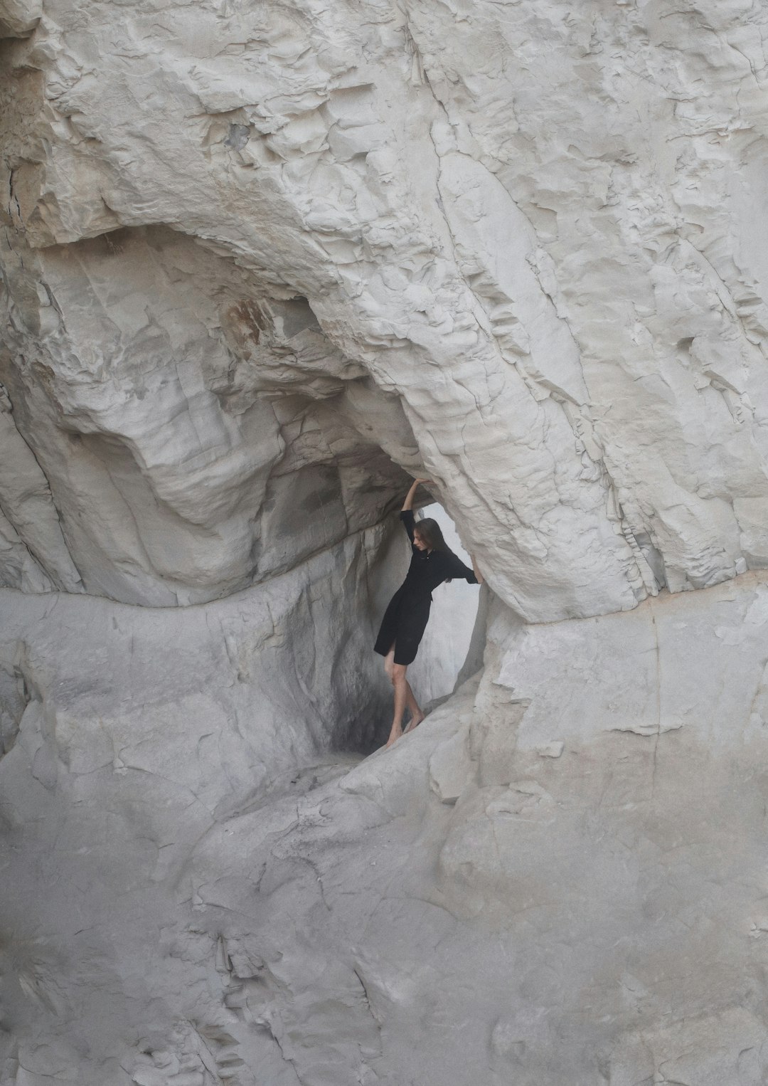 woman in black long sleeve shirt climbing on rock formation during daytime