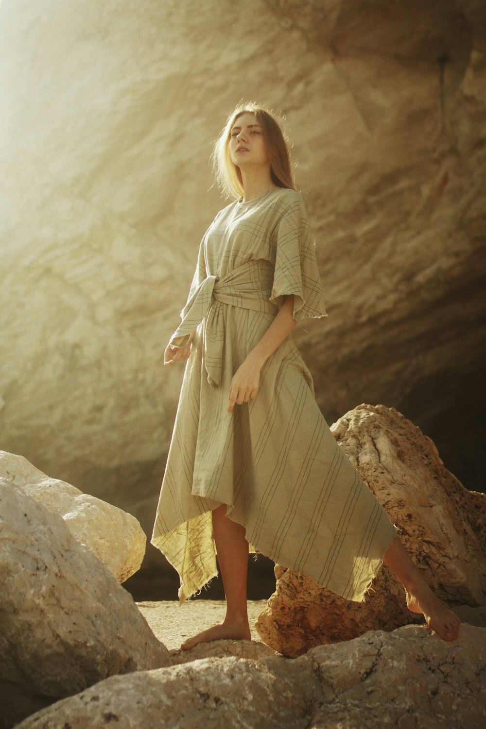 woman in brown dress standing on rock