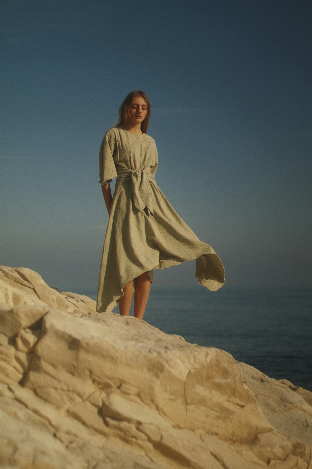 woman in brown dress standing on brown rock formation during daytime