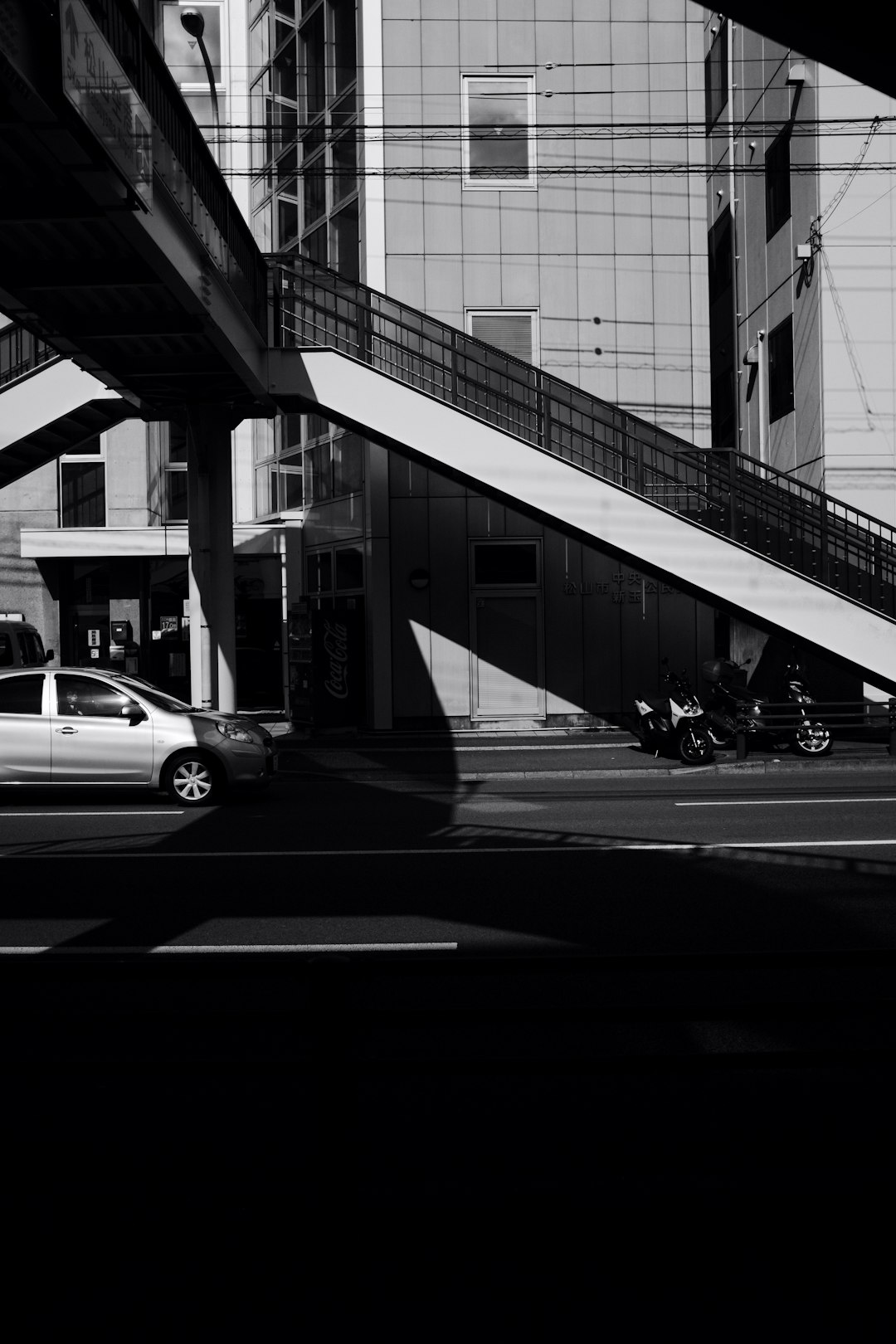 grayscale photo of cars on road near building