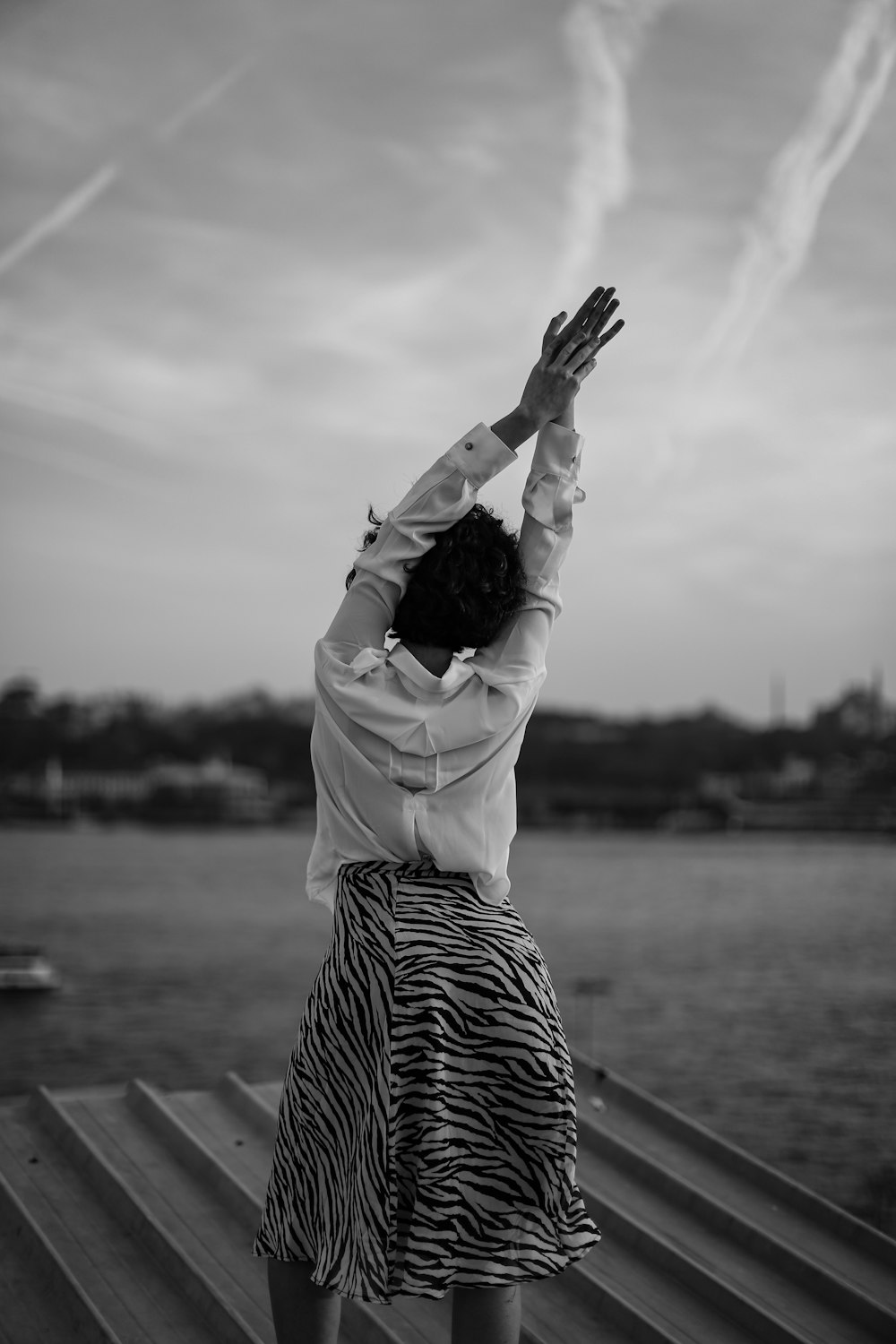 grayscale photo of woman in white long sleeve shirt and striped skirt