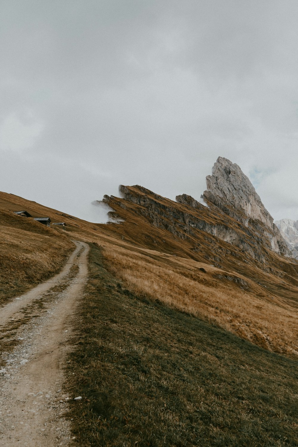 Campo de hierba marrón y verde cerca de la montaña marrón bajo nubes blancas durante el día