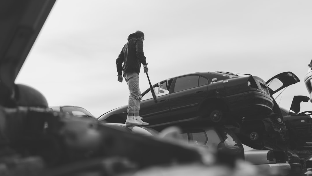 grayscale photo of woman standing beside car