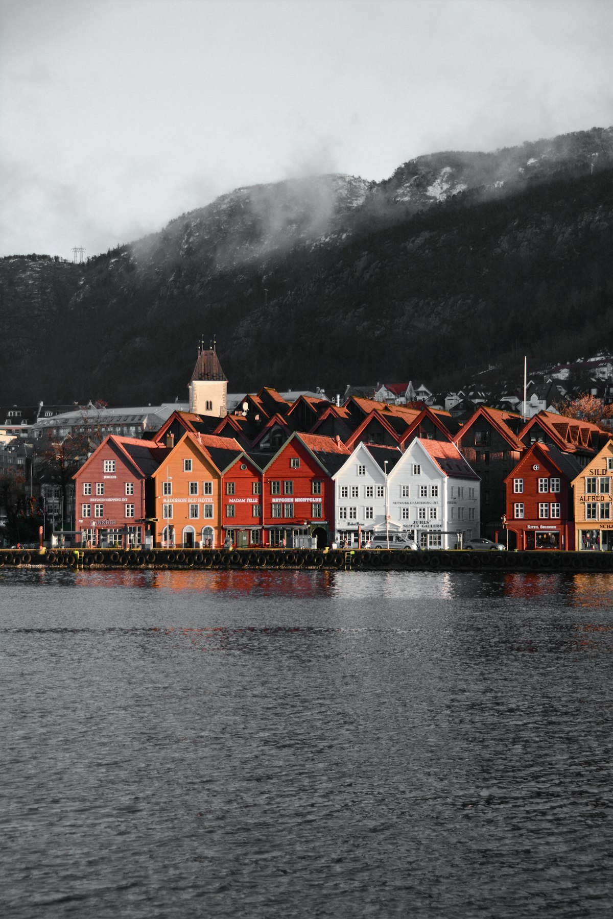 Bergen October — rain-slicked Bryggen quay reflecting coloured warehouse facades