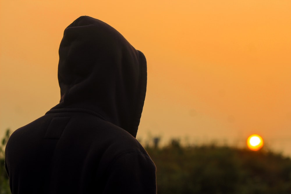 Persona con sudadera con capucha negra de pie durante el día