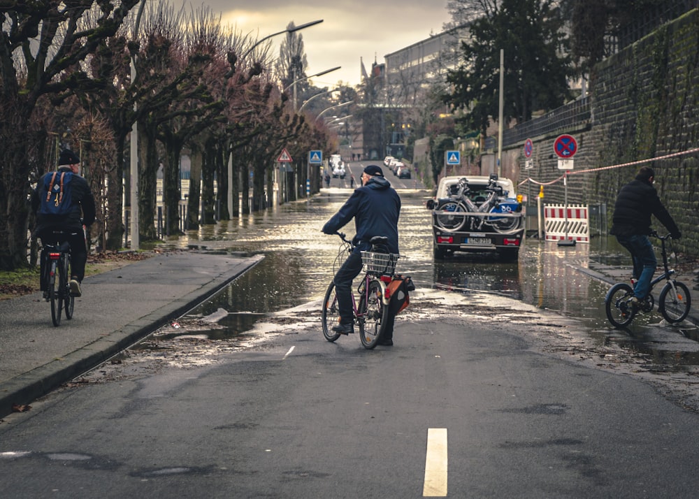 uomo in giacca nera che va in bicicletta su strada durante il giorno