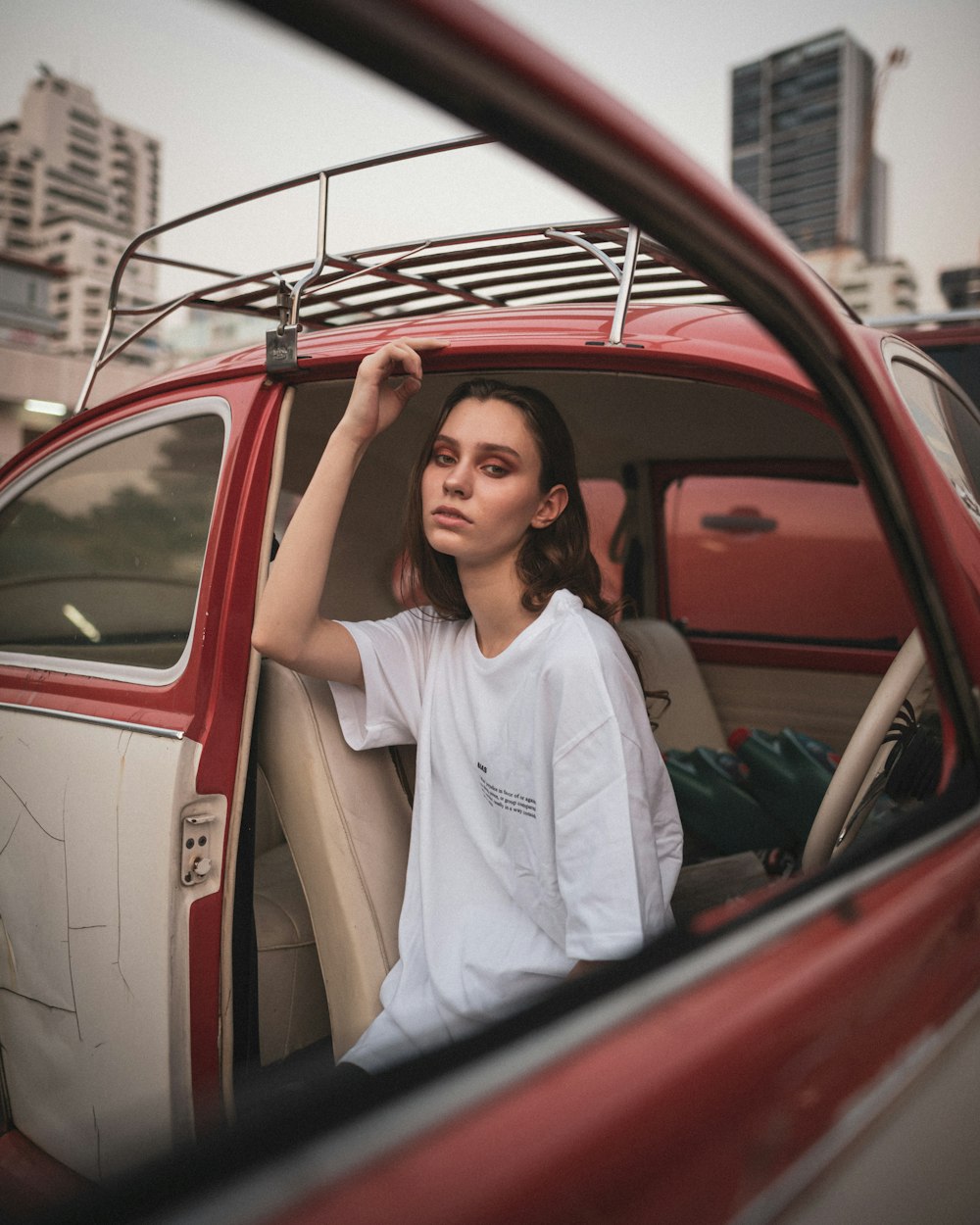 woman in white button up shirt standing beside red car during daytime