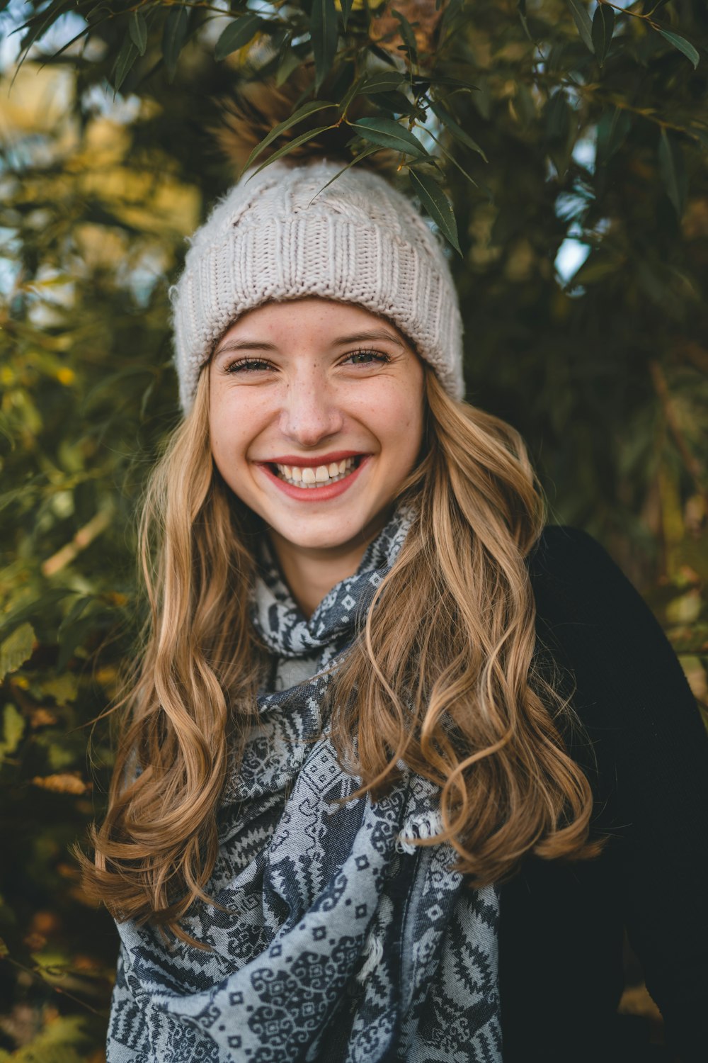 smiling woman in black and white floral shirt wearing gray knit cap