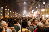 A modern food market bustling with people exploring vibrant stalls under warm lighting.